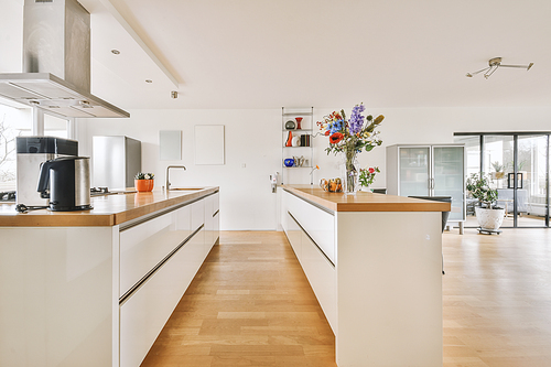 Modern minimalist style interior design of studio apartment with open white kitchen, and dining zone with table and chairs