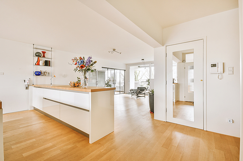 Modern minimalist style interior design of studio apartment with open white kitchen, and dining zone with table and chairs