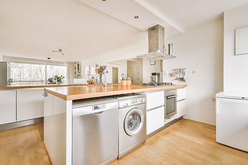 Modern minimalist style interior design of studio apartment with open white kitchen, and dining zone with table and chairs