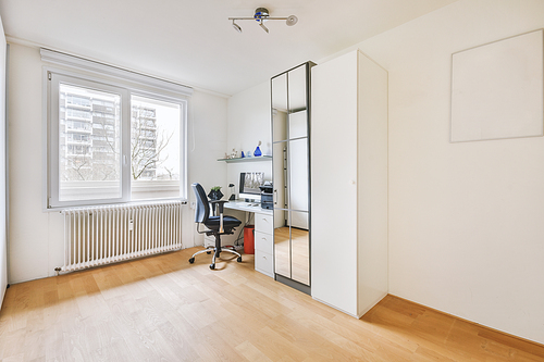 Workspace in light modern room with computer, wardrobe, mirror and window