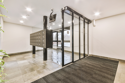 Lobby of a white residential building with mailboxes and glass doors