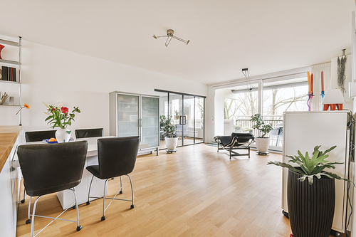 Modern minimalist style interior design of studio apartment with open white kitchen, and dining zone with table and chairs