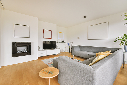 Interior of light living room with stylish sofa and decorations and glass door and windows leading to balcony on sunny day