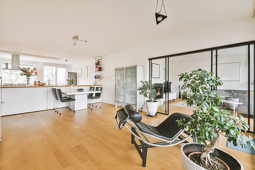 Modern minimalist style interior design of studio apartment with open white kitchen, and dining zone with table and chairs