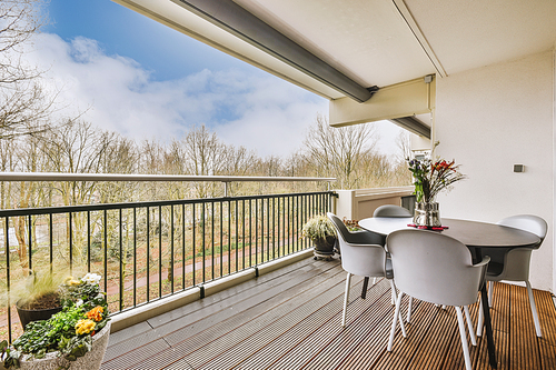 Modern balcony design, coffee table with chairs, green plants and glass railings