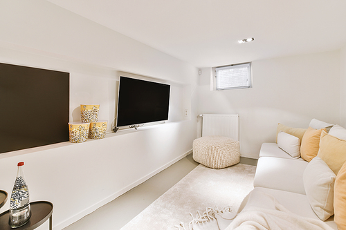 A guest area with a large white sofa in front of a large TV in a modern house