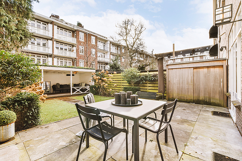 The backyard of a residential building with a green lawn and a place to relax