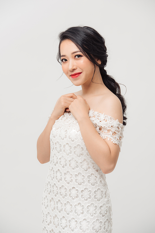 Beautiful Asian young woman in white dress posing on the white background. Beauty, fashion. Haircare. Cosmetics.