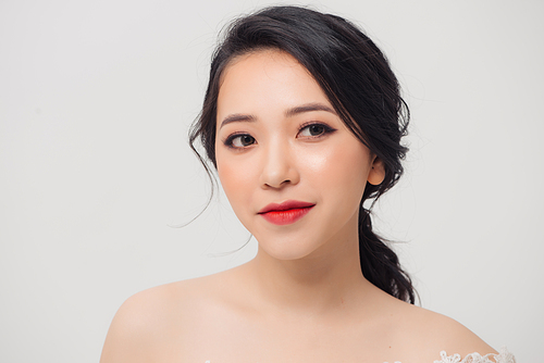 Portrait of young elegant Asian woman with white dress isolated on light background.