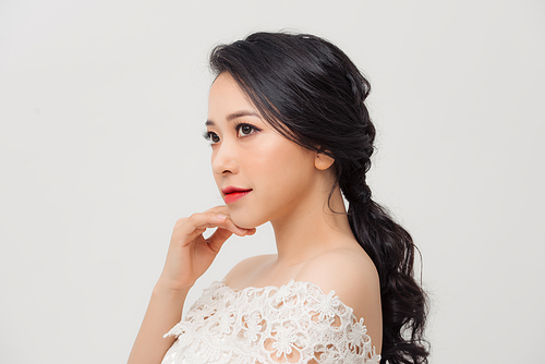 Portrait of young elegant Asian woman with white dress isolated on light background.