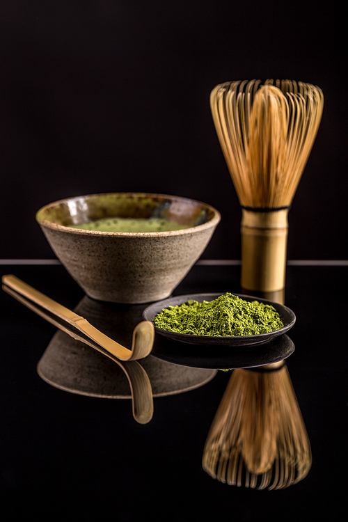 Organic green matcha tea in a bowl and matcha utelsils