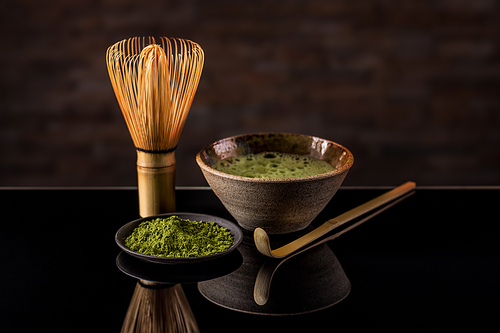 Green tea matcha in a bowl with whisk and spoon