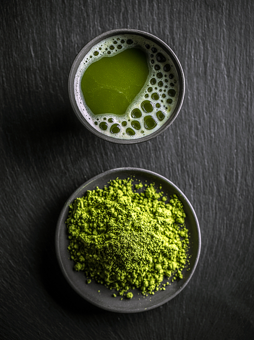 Top view of organic green matcha tea in a bowl and matcha powder