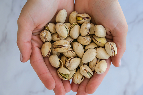 Woman hands holding pistachio in shell nuts. Healthy food and snack. Pistachios great for healthy and dietary nutrition. Concept of nuts. Organic vegan protein