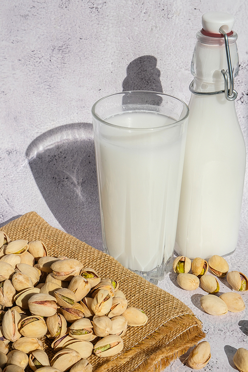 Glass of healthy pistachio milk stands on concrete background. Diet milk, vegetarian food. Gluten free. Close-up. Pistachio lactose free milk for dietary nutrition. Alternative food and vegetarianism. Nut non-dairy milk
