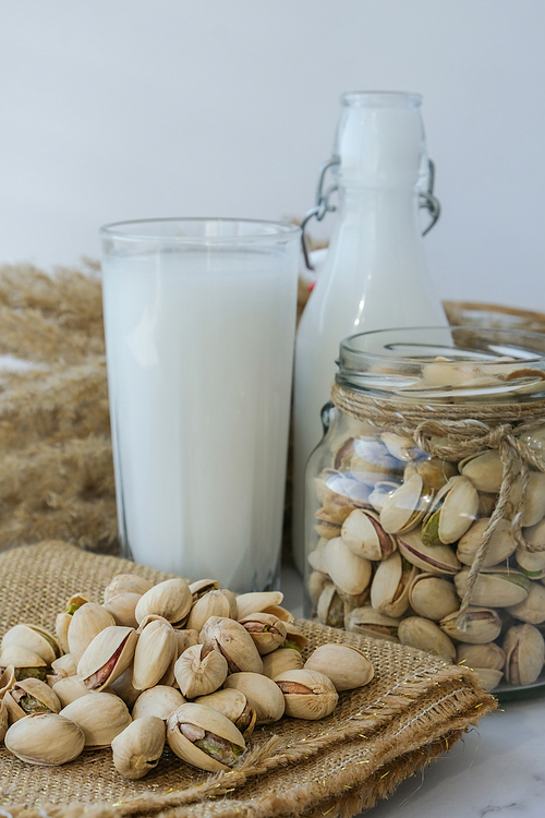 Glass of healthy pistachio milk stands on concrete background. Diet milk, vegetarian food. Gluten free. Close-up. Pistachio lactose free milk for dietary nutrition. Alternative food and vegetarianism. Nut non-dairy milk