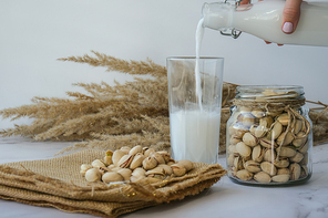Vegetable milk is poured into a glass Pistachio lactose free milk for dietary nutrition. Alternative food and vegetarianism. Diet milk, vegetarian food. Gluten free. Nut non-dairy milk