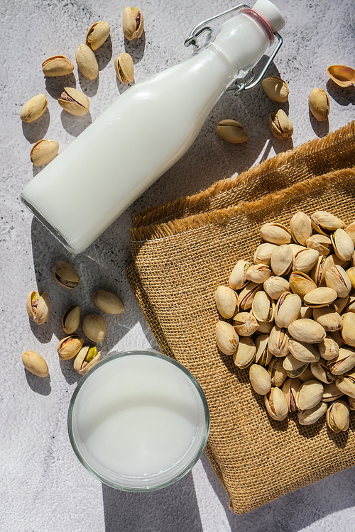 Glass of healthy pistachio milk stands on concrete background. Diet milk, vegetarian food. Gluten free. Close-up. Pistachio lactose free milk for dietary nutrition. Alternative food and vegetarianism. Nut non-dairy milk