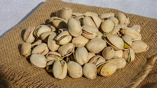Pistachios in burlap sack on concrete table. Organic pistachios. Vegan Healthy food high protein. Dietary nutrition. Concept of nuts omega vitamin