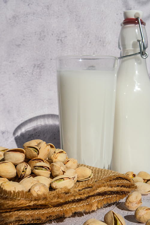 Glass of healthy pistachio milk stands on concrete background. Diet milk, vegetarian food. Gluten free. Close-up. Pistachio lactose free milk for dietary nutrition. Alternative food and vegetarianism. Nut non-dairy milk