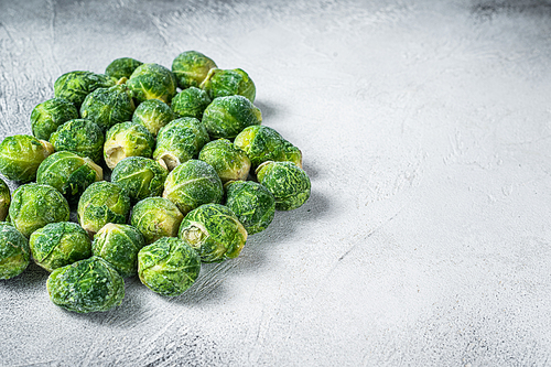 Frozen Brussels sprouts green cabbage on kitchen table. White background. Top view. Copy space.