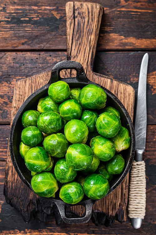 Boiled Brussels green sprouts cabbage in a pan. Dark wooden background. Top view.
