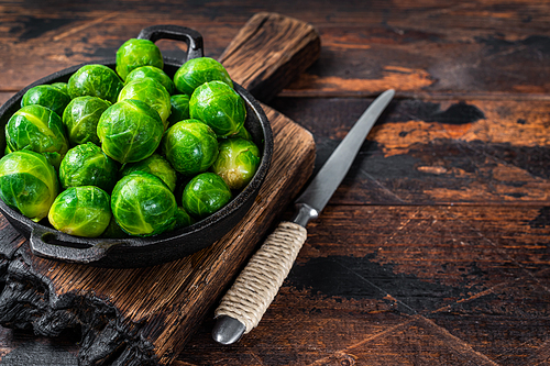 Boiled Brussels green sprouts cabbage in a pan. Dark wooden background. Top view. Copy space.