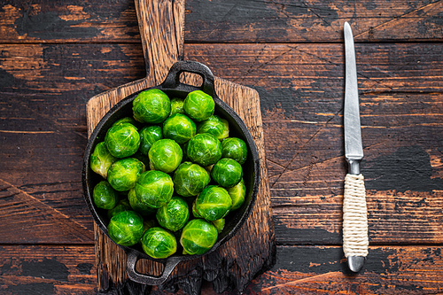 Boiled Brussels green sprouts cabbage in a pan. Dark wooden background. Top view.