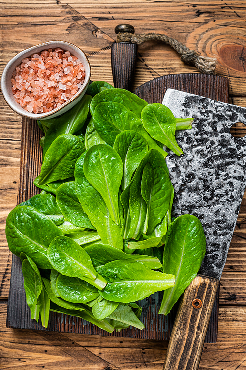 Baby romain green salad leaves on wooden cutting board. wooden background. Top view.