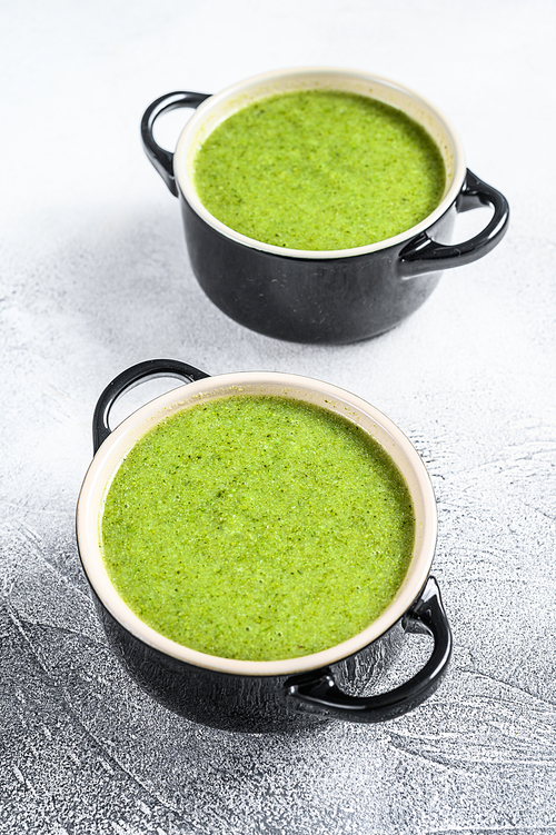 Homemade broccoli and spinach cream soup in bowl. White background. Top view.