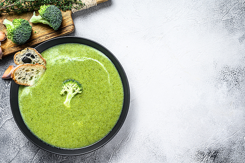 Homemade Broccoli soup with fresh baguette. White background. Top view. Copy space.