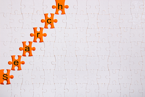Jigsaw puzzle with word ‘search’ on orange background. Conceptual image.