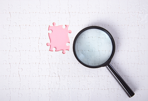 Set of puzzle pieces with magnifying glass background. Detective research concept