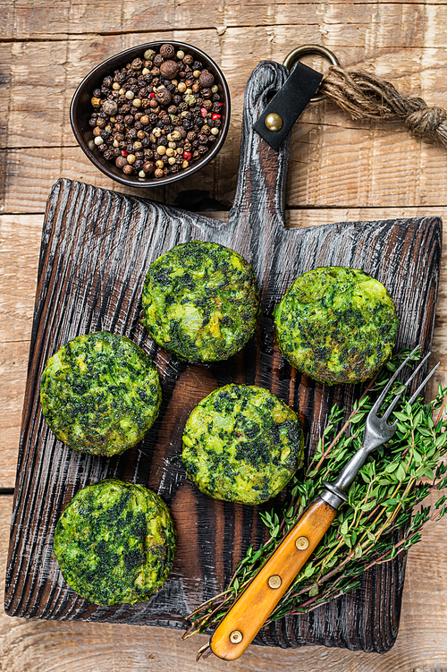 Vegetarian vegetable burgers patty with herbs on wooden board. Wooden background. Top view.