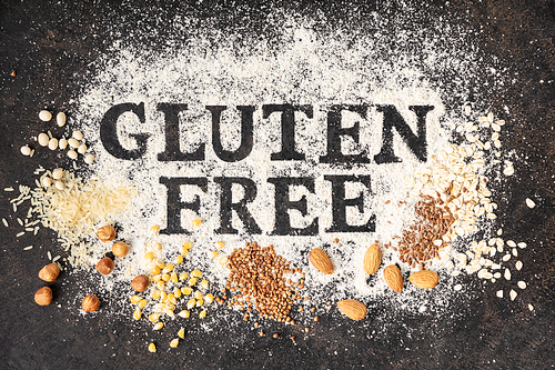 Gluten free written in flour on vintage baking sheet and gluten free grains and nuts, gluten free baking concept