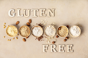various gluten free flour almond flour, oatmeal flour, buckwheat flour, ., corn flour and gluten free lettering made of wooden letters, top view, flat lay