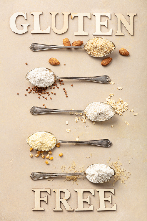 metal spoons of various gluten free flour (almond flour, oatmeal flour, buckwheat flour, ., corn flour) and gluten free lettering made of wooden letters