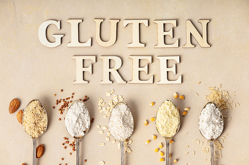 metal spoons of various gluten free flour (almond flour, oatmeal flour, buckwheat flour, ., corn flour) and gluten free lettering made of wooden letters