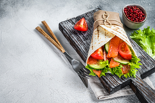 Wrap sandwich, roll with fish salmon and vegetables. White background. Top view. Copy space.