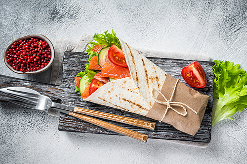 Wrap sandwich, roll with fish salmon and vegetables. White background. Top view.