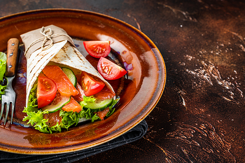 Wrap roll sandwich with fish salmon and vegetables. Dark background. Top view. Copy space.