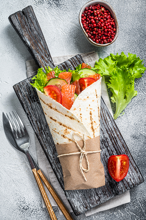 Wrap sandwich, roll with fish salmon and vegetables. White background. Top view.