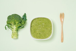 Tasty broccoli soup on a green background