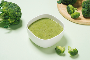 Tasty broccoli soup on a green background