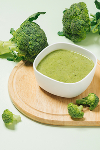 Tasty broccoli soup on a green background
