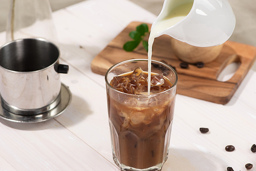 Bartender pours milk into glass of coffee