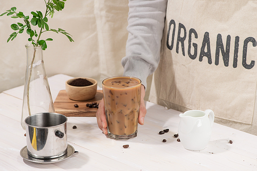 Cropped image of handsome barista in apron holding a cup of coffee