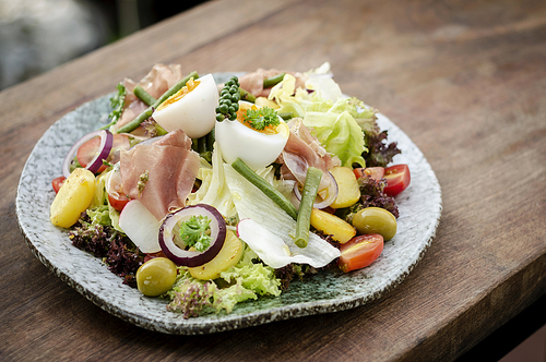nicoise style healthy organic rustic salad with egg and ham outdoors