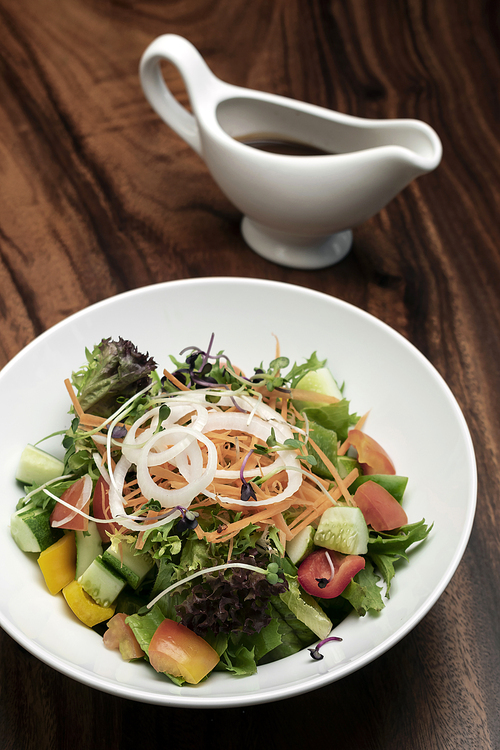 fresh organic mixed vegetable vegan Garden Salad with Vinaigrette sauce on wooden table