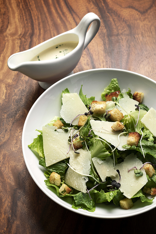 caesar salad with parmesan cheese and croutons on wood table